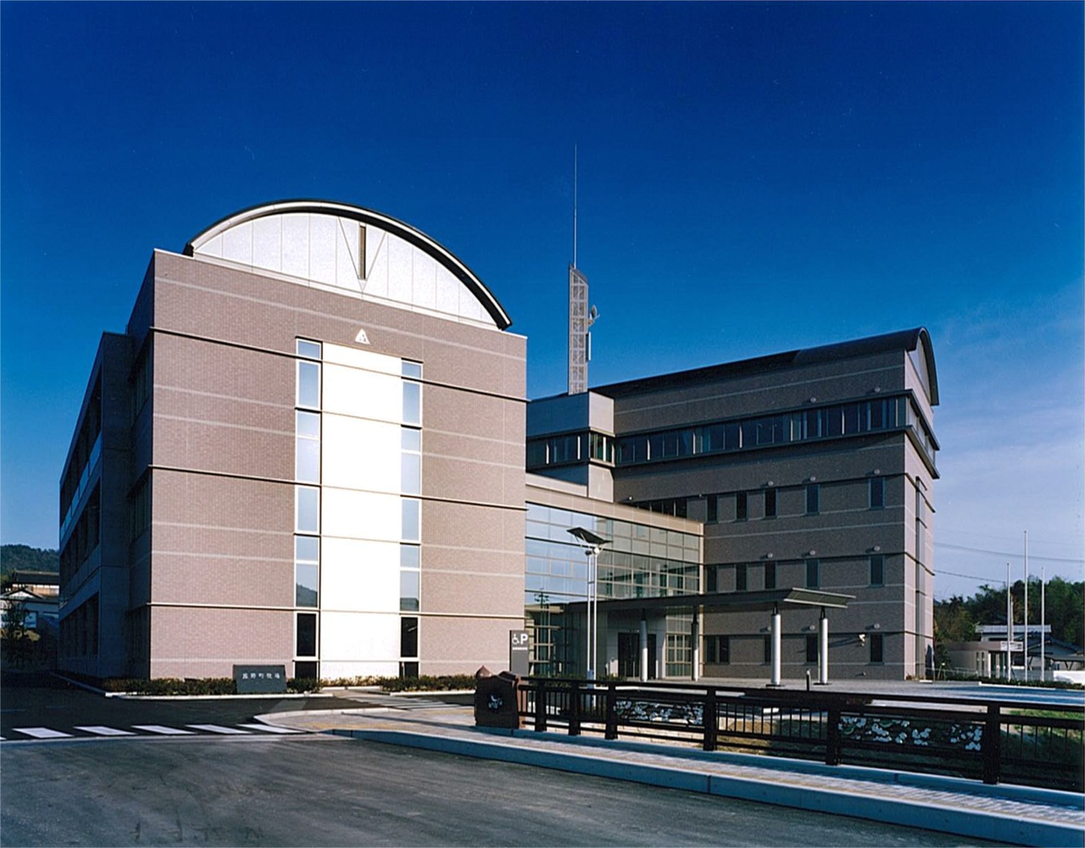 青空の下薄茶色の建物と横断歩道がある写真