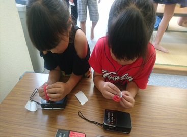 2名の児童が机の上でテープを用いて作業を行っている写真