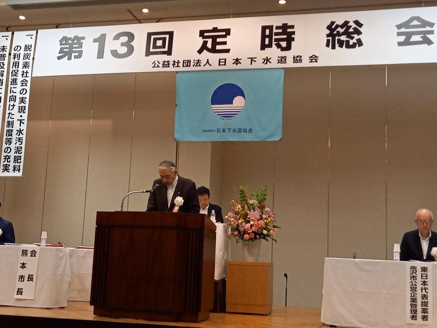 定時総会の壇上で意見を発表する熊野町長の写真