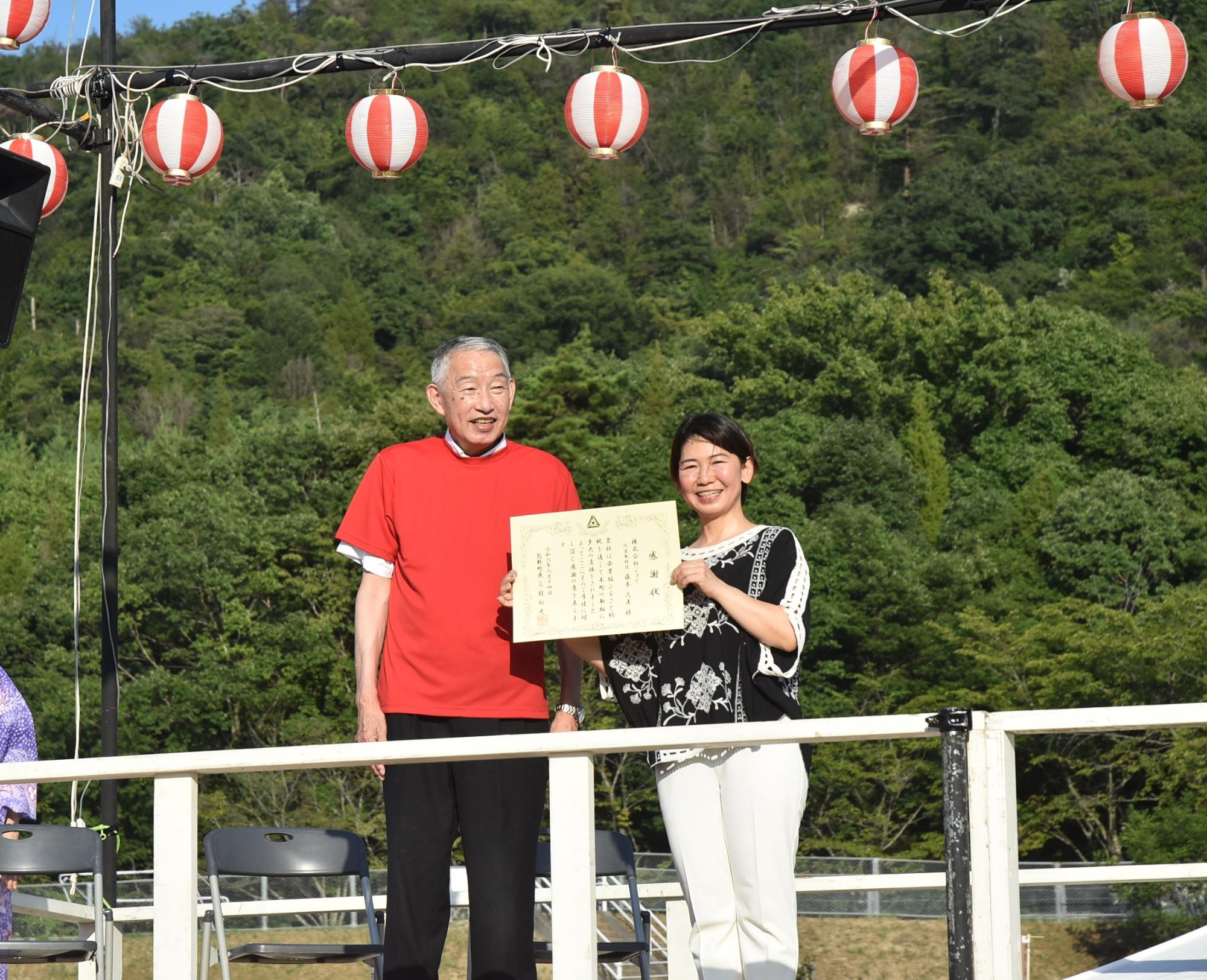 町民夏祭り会場で熊野町長と記念撮影に臨む藤本代表取締役の写真