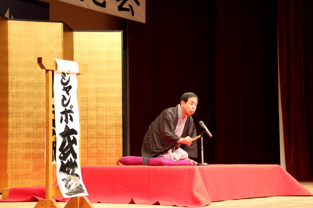 式典の高座で落語を披露するジャンボ衣笠さんの写真