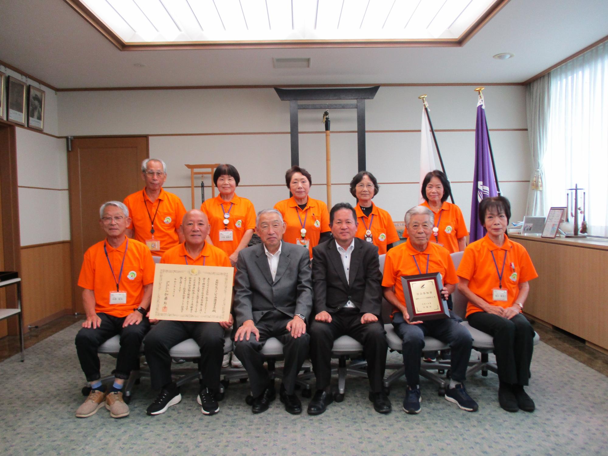 オレンジ色のシャツを着て熊野町長との記念撮影に臨むボランティア団体の方々の写真