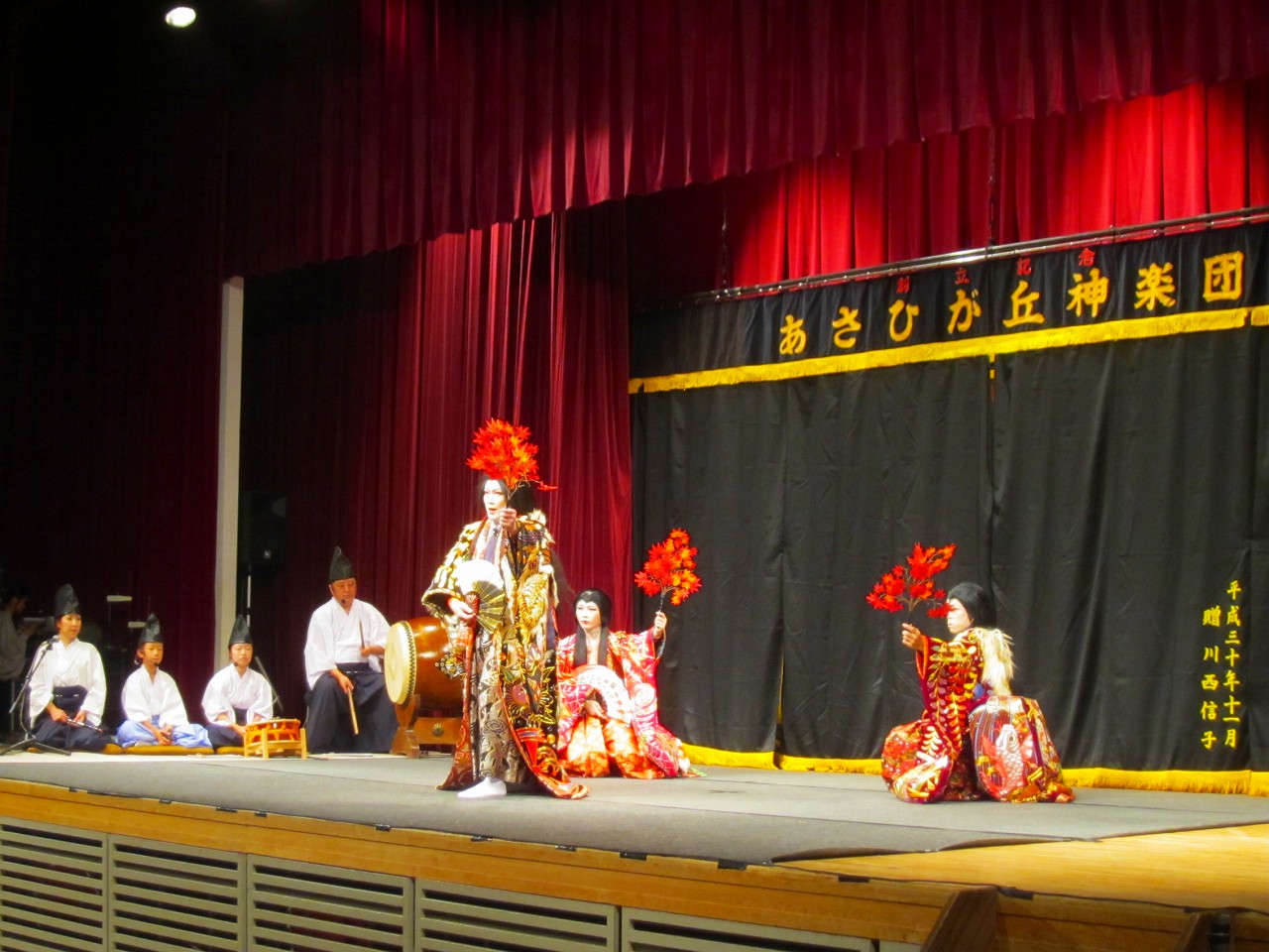 舞台で神楽公演を披露しているあさひが丘神楽団の皆さんの写真