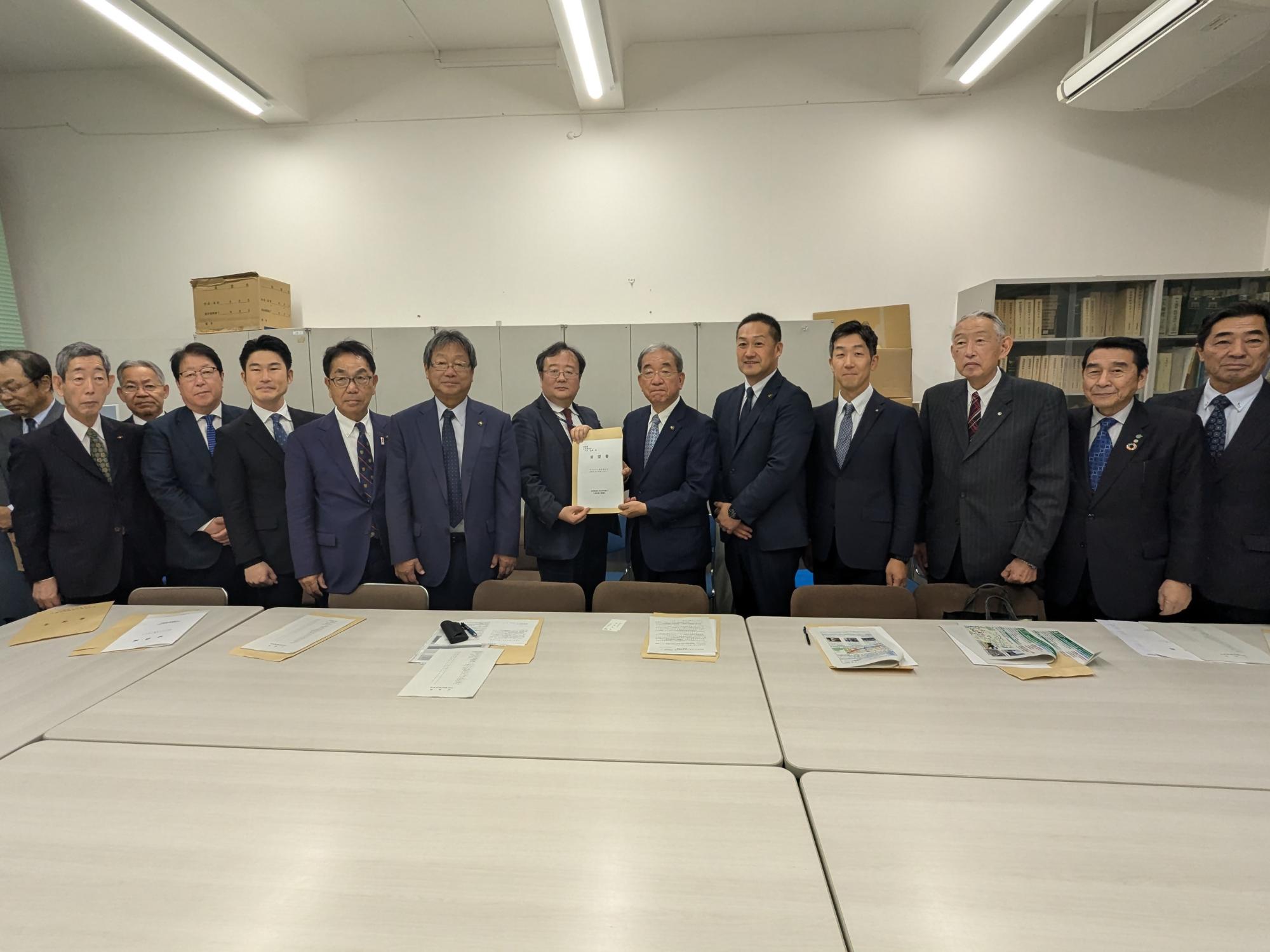 長テーブルの前で記念撮影に臨む財務省中山主計局次長たちと熊野町長の写真