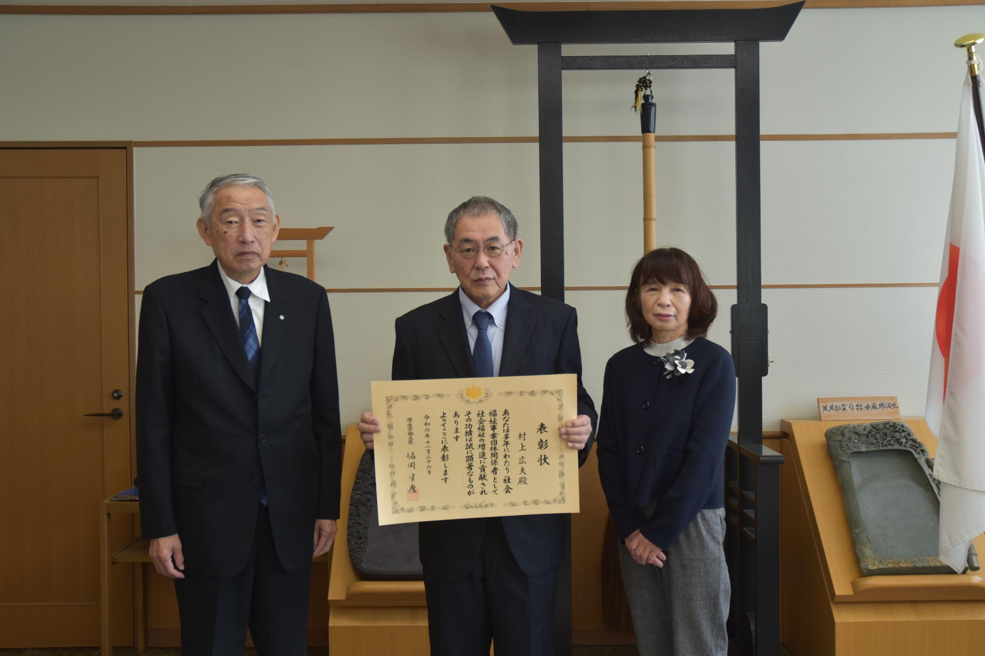 熊野町長といっしょに表彰状を持って記念撮影に臨む村上広夫さんの写真