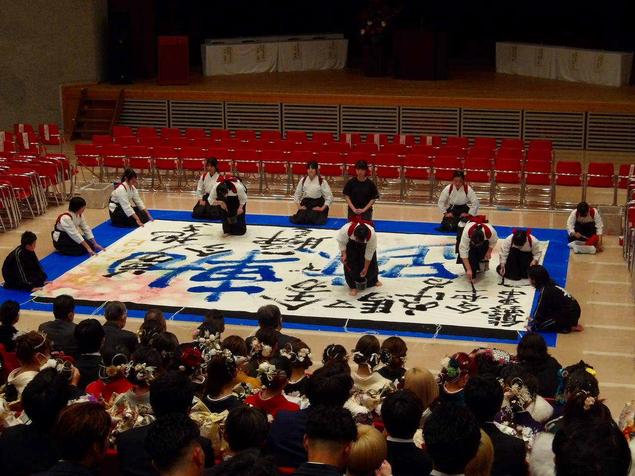 大きな半紙と大筆を用いてパフォーマンスを行う大書揮毫の様子を捉えた写真