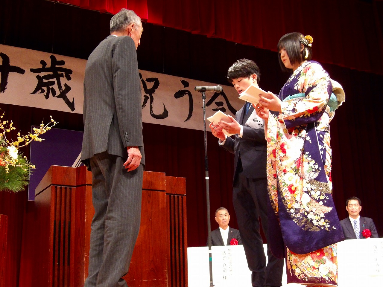 二十歳を祝う会の壇上で熊野町長へ誓いの言葉を述べる男女の写真