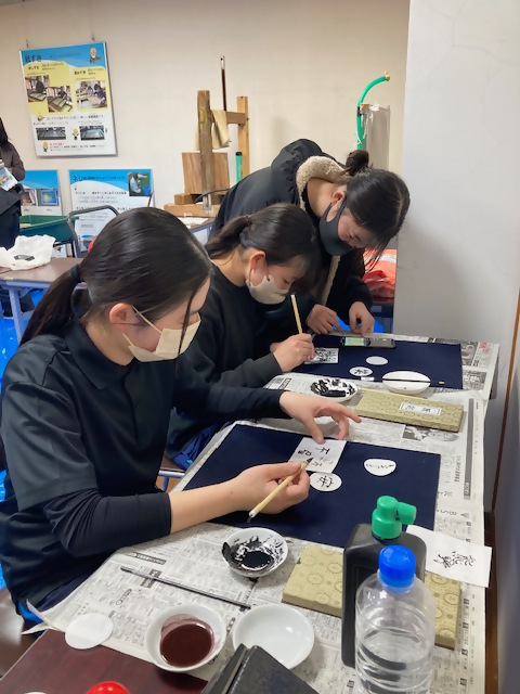 ワークショップで和紙に書をしたためる女性たちの写真