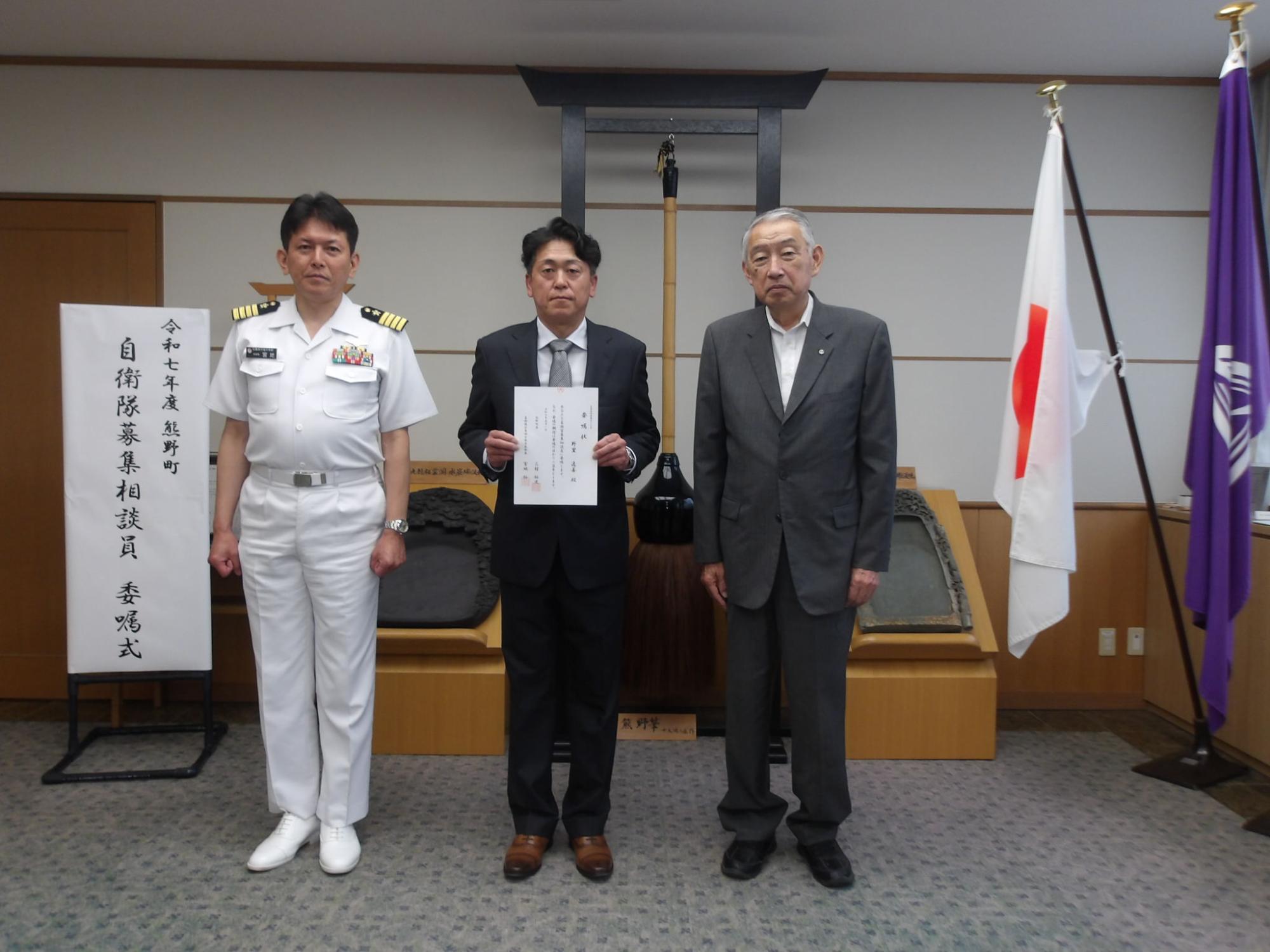 委嘱式での記念撮影に臨む野里逸善さん、自衛隊広島地方協力本部長、熊野町長の写真