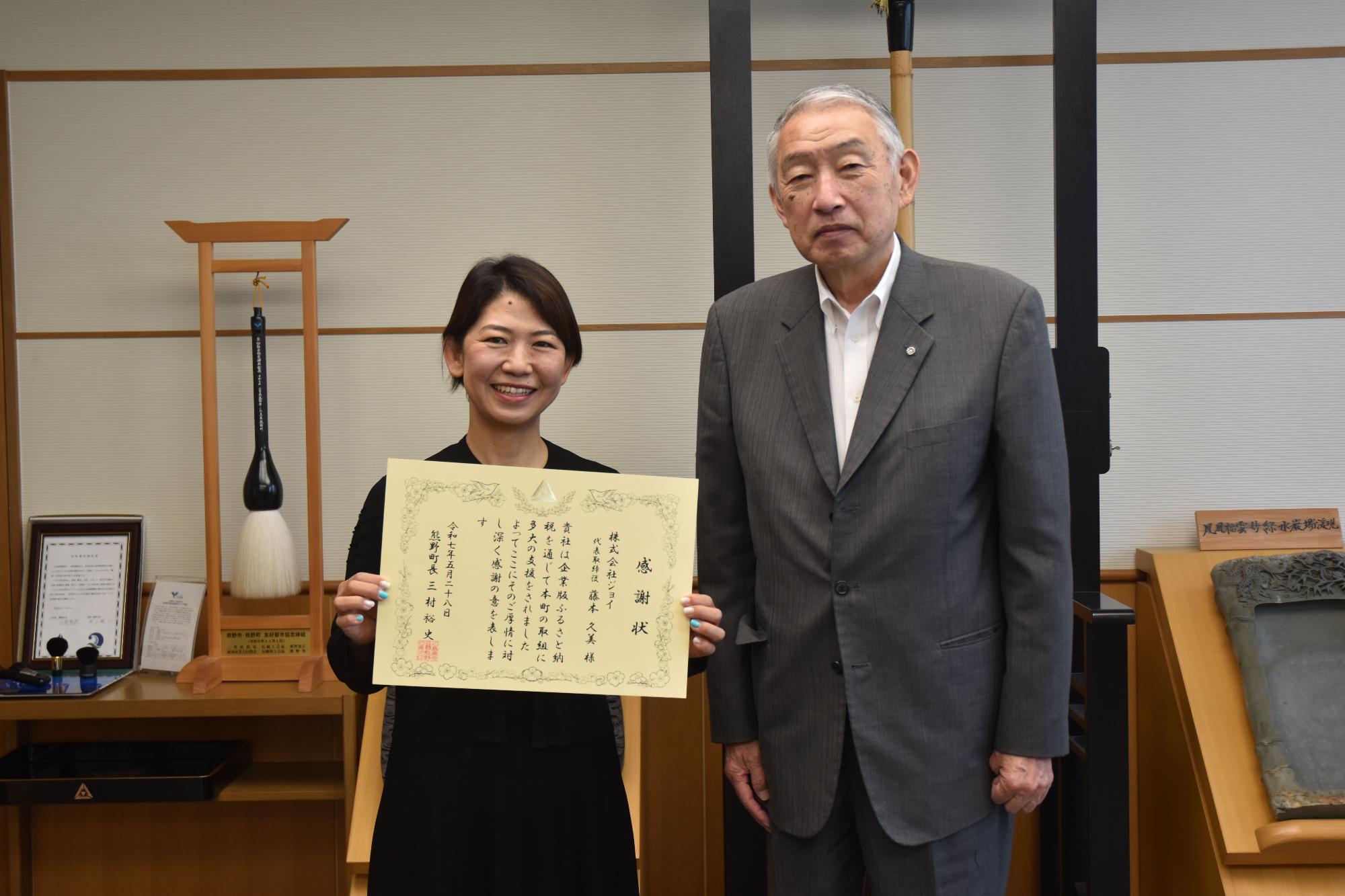 感謝状を持って記念撮影に臨む藤本代表取締役と熊野町長の写真