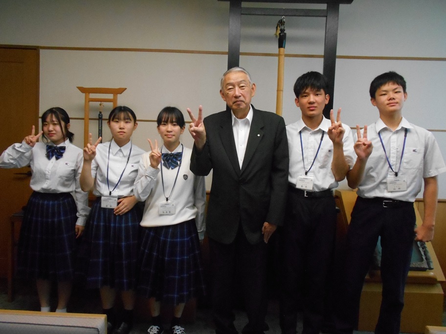 ピースサインをしながら高校生といっしょに記念撮影に臨む熊野町長の写真