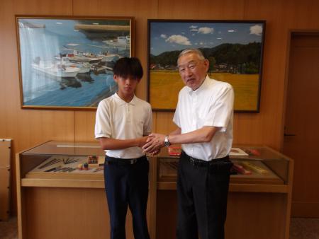 役場の一室で熊野町長と固い握手をかわす熊野東中学校池本孝太朗さんの写真