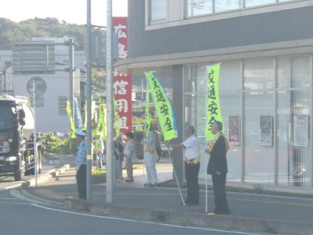 「交通安全」ののぼりを持ちながら、交差点で交通安全を呼び掛けている地域住民の方々の写真