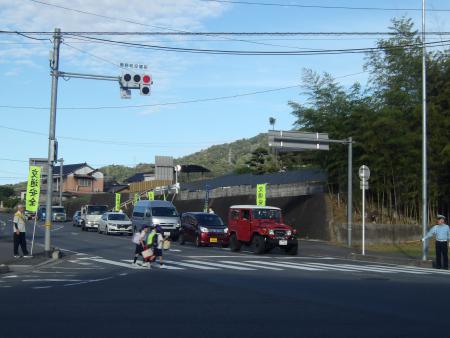 小学生たちが横断歩道を横断しているのを見守っている地域住民の方や警察官の写真
