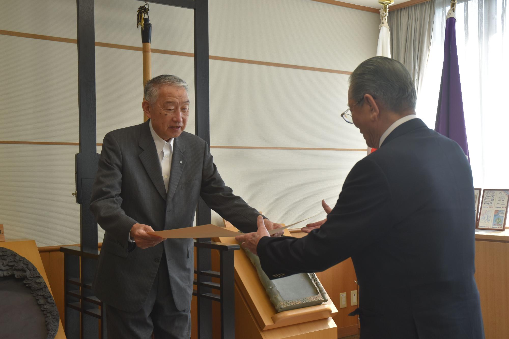 会議室で町長から叙勲の賞状を受け取る男性の写真