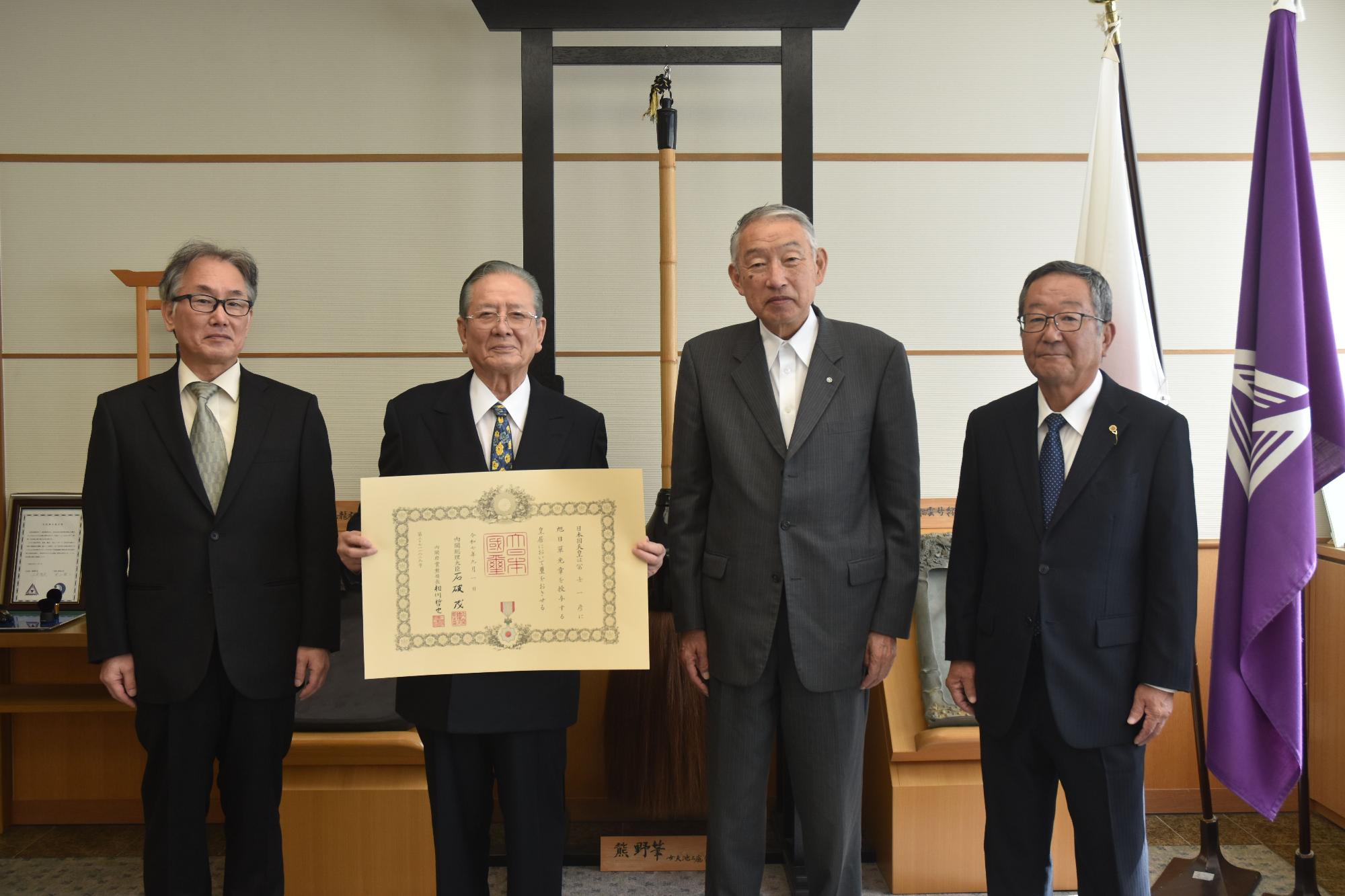 町長ほか2名の男性と共に写真にうつる賞状を手にした男性の写真