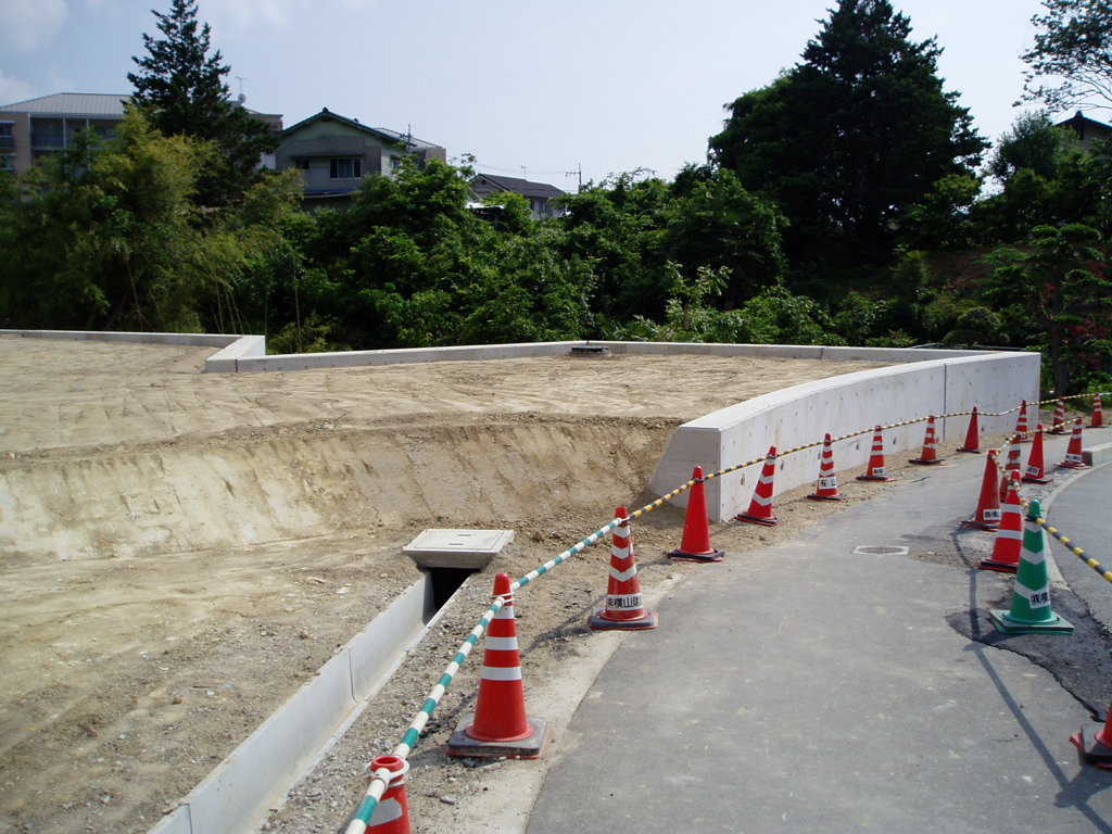 擁壁の内側に土が敷き詰められ、側溝が設置された計画地の写真