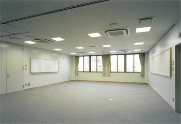 正方形の天井照明が並び、窓から光が差している会議室の写真