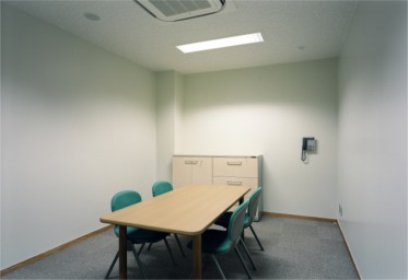 緑色の椅子が机越しに向かい合って4脚置かれている対面朗読室の写真