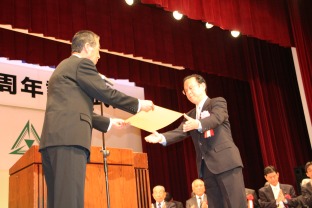 表彰状を授与し、それを受け取る受賞者の写真