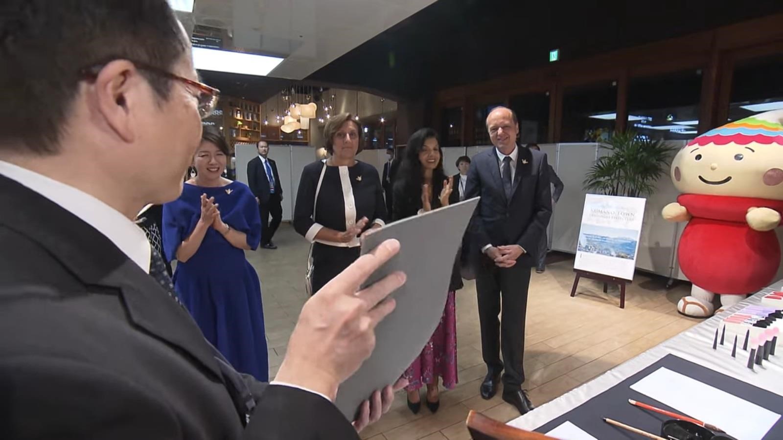 来賓に熊野筆や水書体験について説明をしている写真