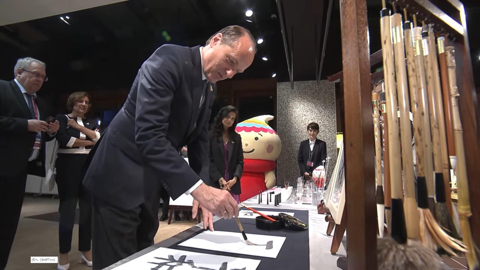 筆を持って水書をする来賓者の写真