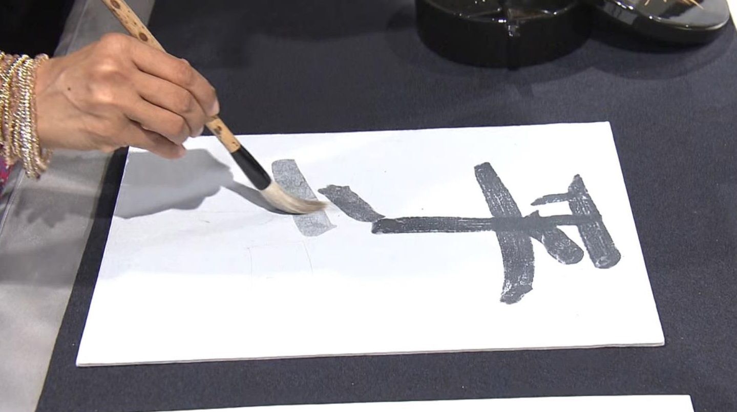 熊野筆で「平和」の文字を水書している写真