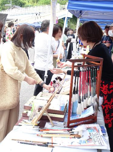 「オール熊野マルシェ」でスタッフから説明を受けながら化粧筆を手に取る女性客の写真