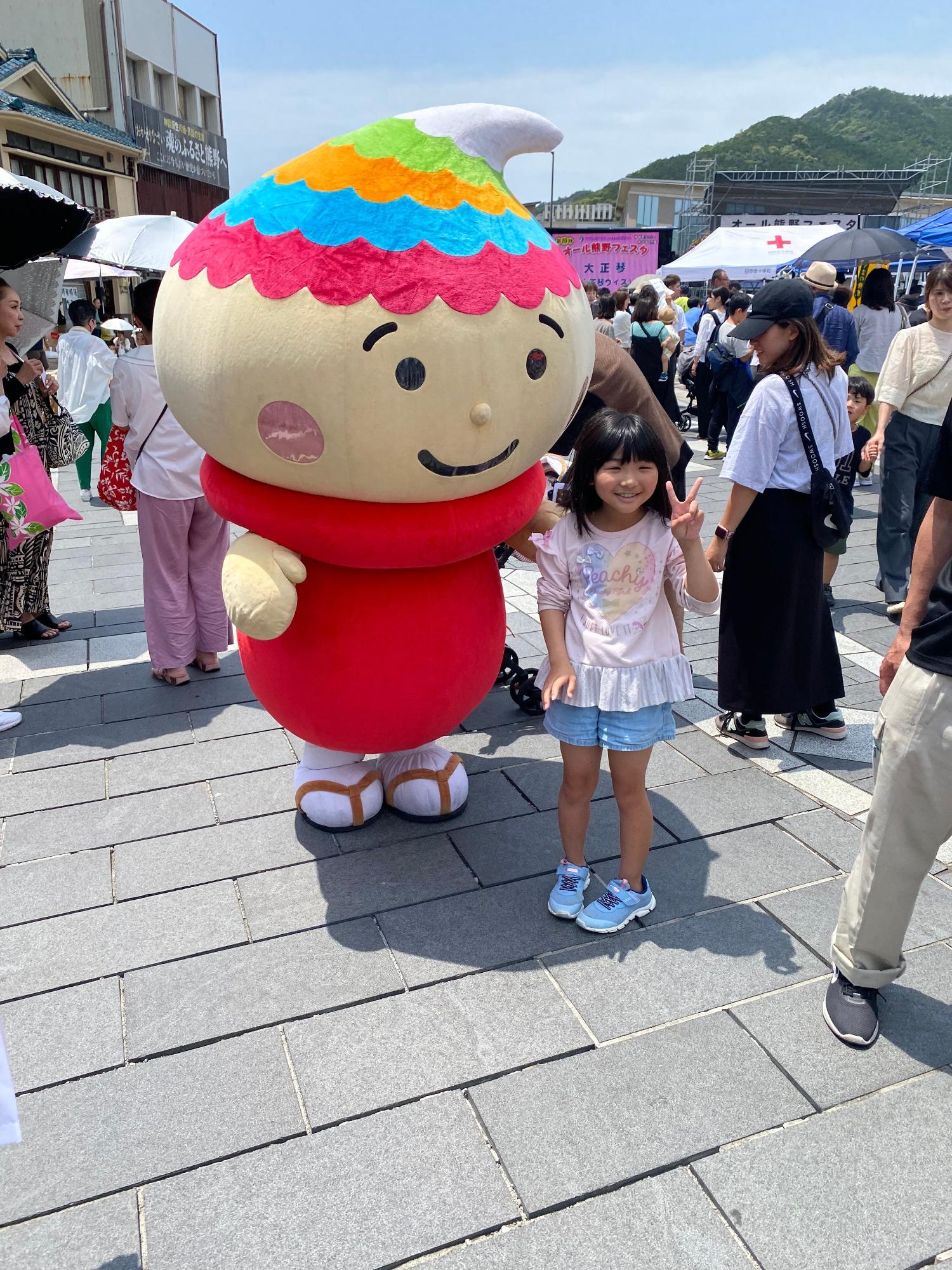 女の子がピースをしながらふでりんと記念撮影している写真