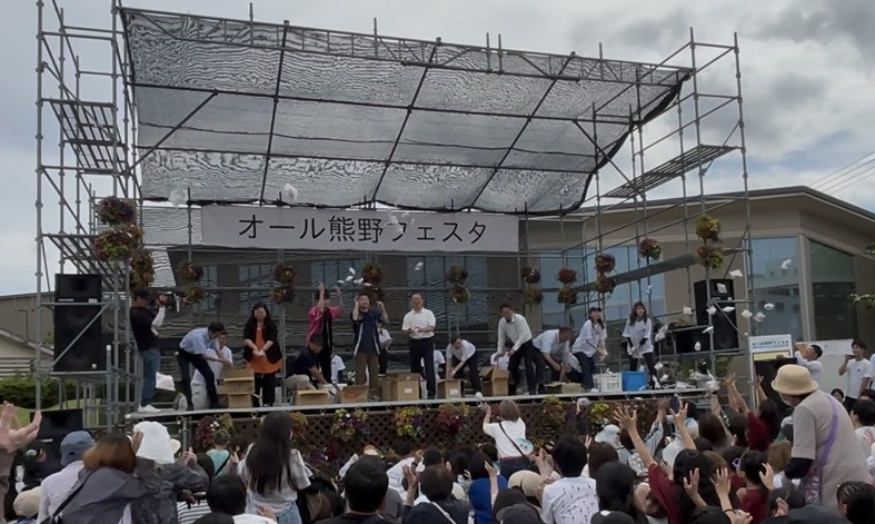 「もちほり（餅まき）」でステージ上から投げられた餅を参加者がキャッチしようとしている写真