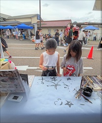 水を使った書板で子どもたちが熊野筆を試し書きしている写真