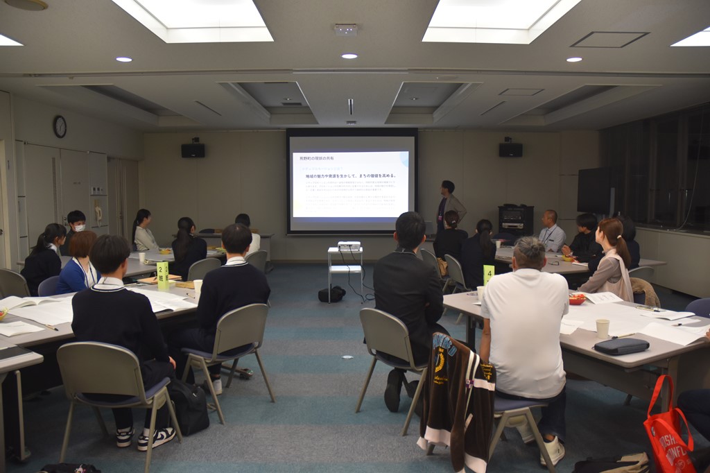 ワークショップにて、スクリーンに映し出された資料をもとに説明を受ける参加者たちの写真