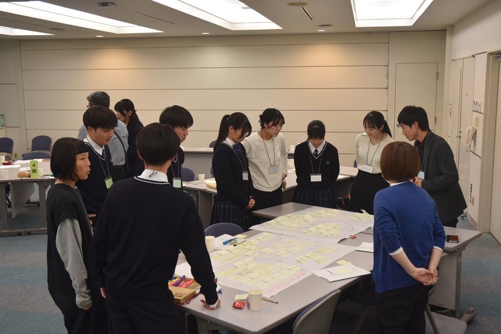 ワークショップにて机に資料を広げて参加者たちが議論している様子の写真