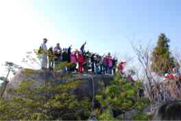 展望デッキに立ち、眼下に広がる周囲の山々を一望している登山者の写真