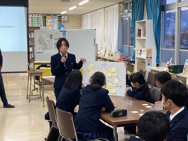 付箋の貼られたホワイトボードと使って意見を述べる高校生たちの写真