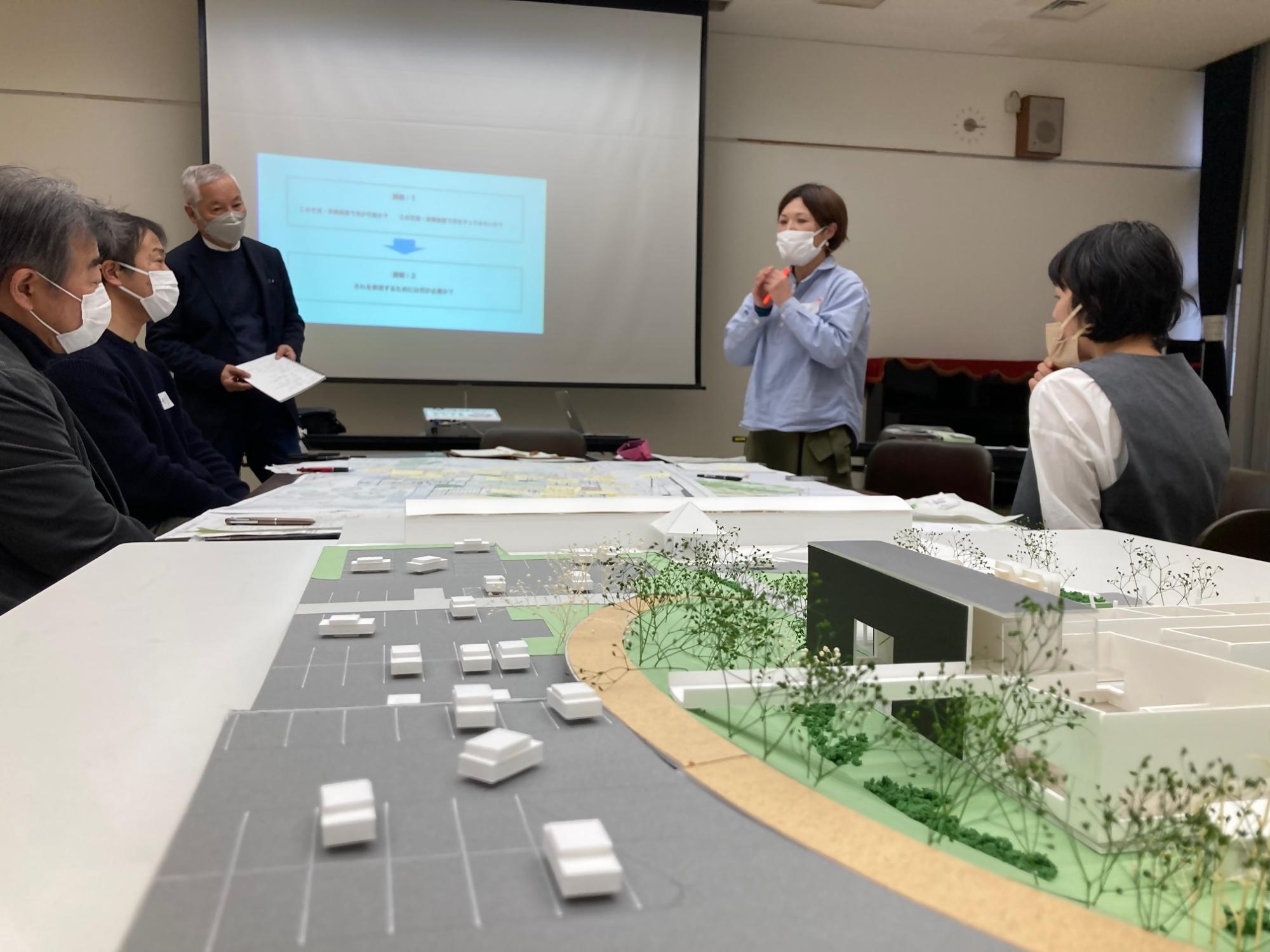 駐車場の模型を前にして意見を発表している参加者たちの写真