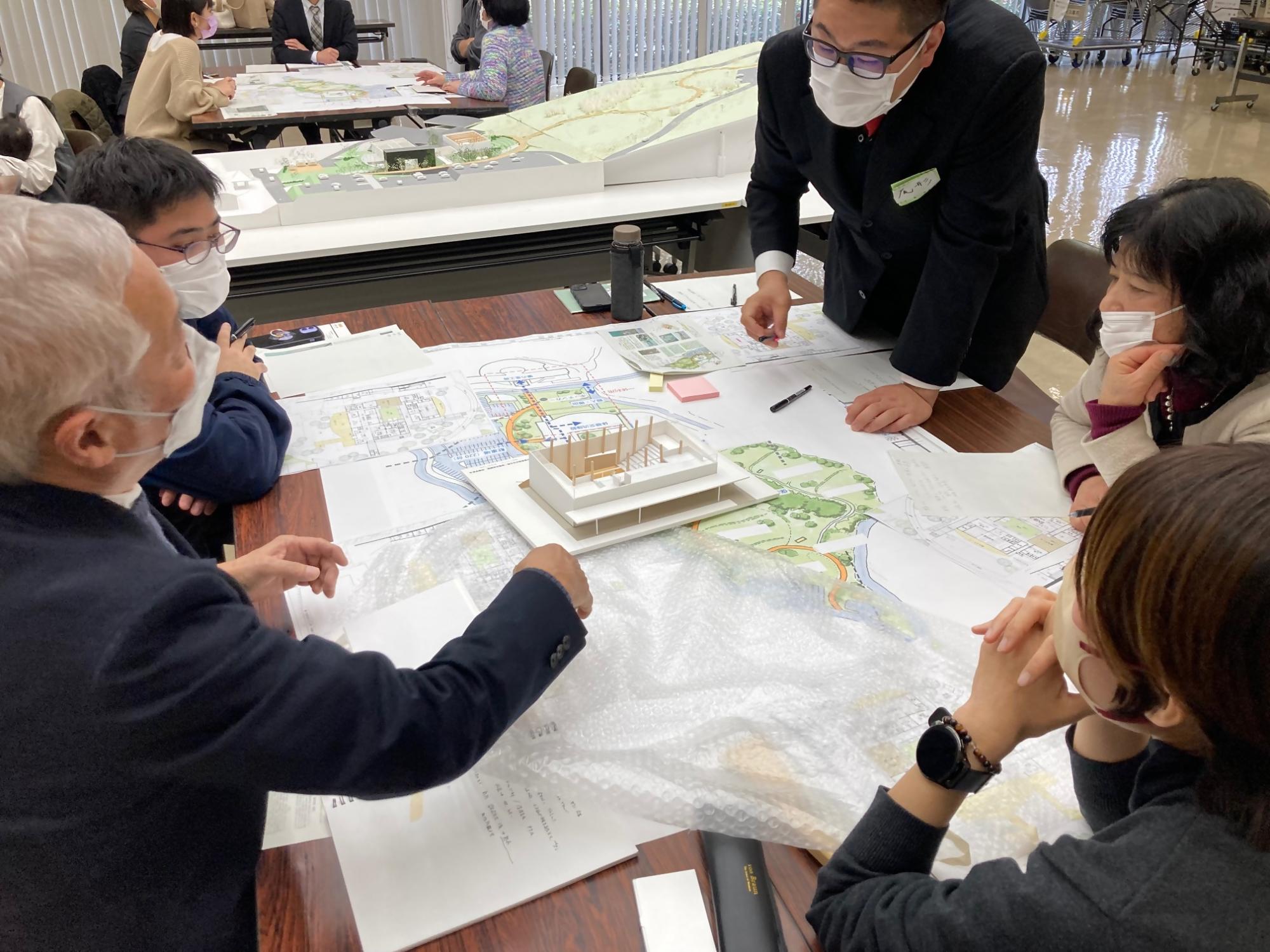 図面の上に置かれた施設の模型をみながら意見をかわす参加者たちの写真