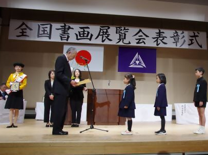 全国書画展覧会表彰式で賞状を受け取ろうとしている子どもたちの写真