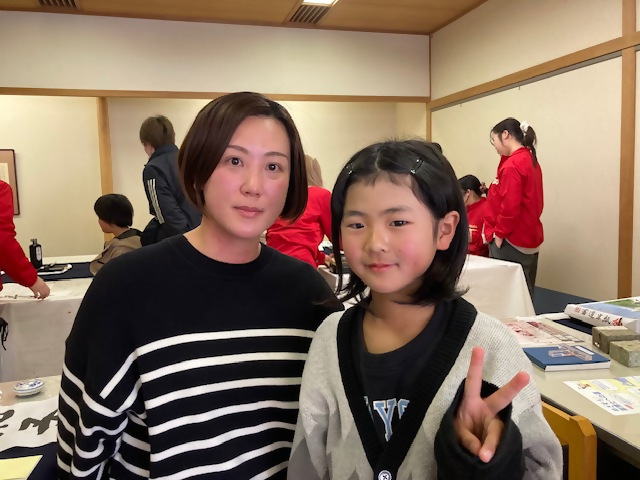 筆の日の会場内でイベントでピースサインをしている親子の写真