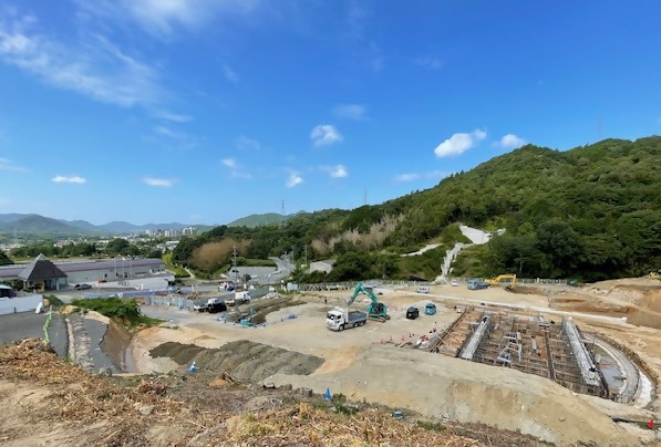 山間の建設現場でショベルカーなどの重機が地面を掘削している写真