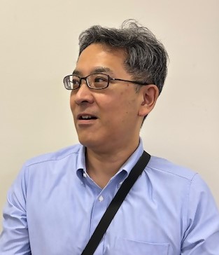 藤色のワイシャツを着ている筆の里工房、主幹（学芸員）吉田さんの写真