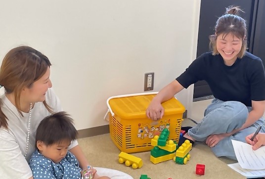 子どもをあやしながらブロック遊びをしている2名の女性の写真