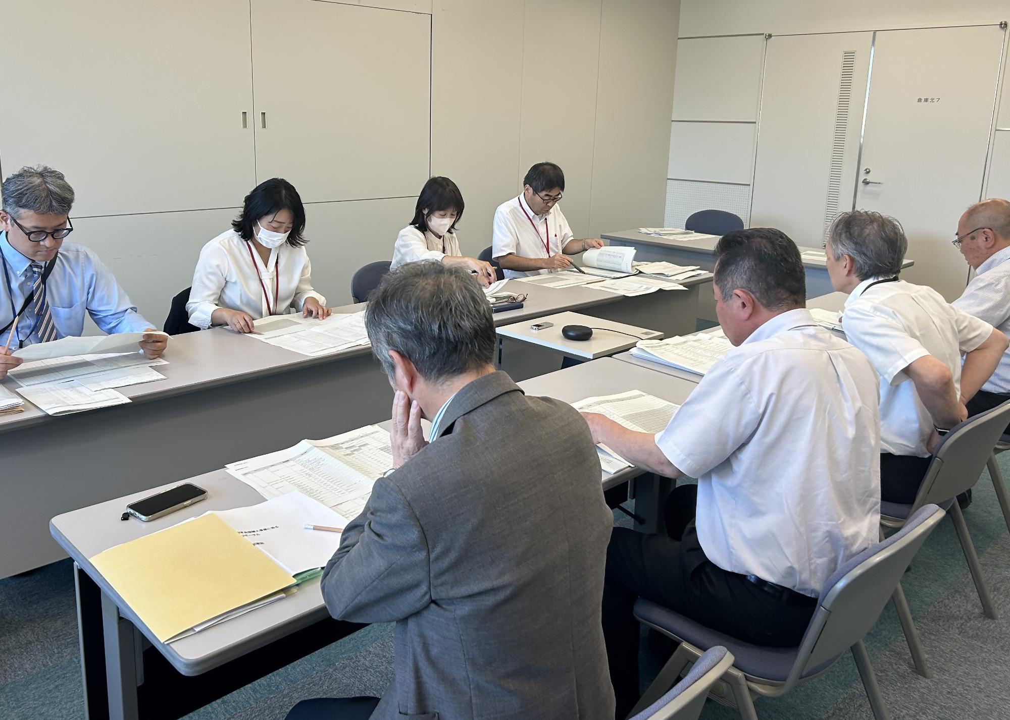 机に置いてある資料を見ている人たちの写真